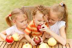 快乐孩子们坐着表格吃苹果