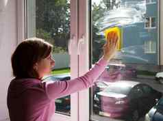 年轻的女人洗窗口放黄色的破布