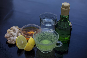 关闭Herbal绿色茶组成威士忌姜蜂蜜水柠檬薄荷透明的杯木表面