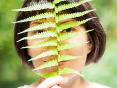 年轻的女人隐藏眼睛蕨类植物叶象征生活宁静团结自然夏天森林