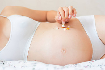 怀孕了女人白色内衣说谎床上药片年轻的女人期待婴儿医学
