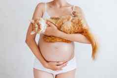 怀孕了女人白色内衣可爱的姜猫年轻的女人期待婴儿风险感染弓形体病