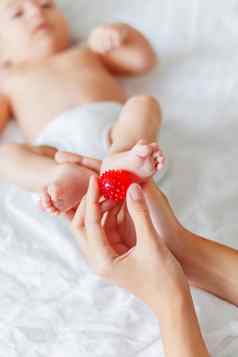 妈妈。持有新生儿婴儿的脚小手指红色的按摩球女人的手舒适的早....首页