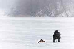 冬天钓鱼男人。鱼冰冻河俄罗斯
