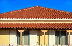 倾斜的光棕色（的）粘土平铺的屋顶农村传统的单层房子南部希腊点峰蓝色的天空