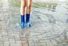 女孩蓝色的橡胶靴子站水坑雨