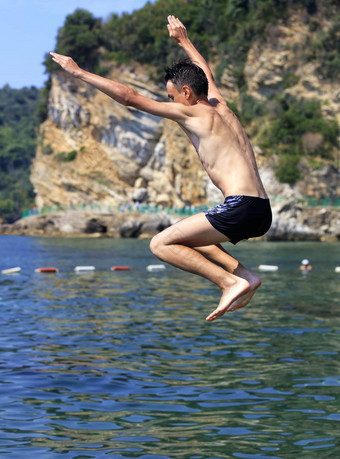 勇敢的青少年跳海背景岩石海岸线