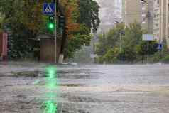 重雨人行道上沥青路照亮绿色交通光