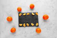 明亮的多汁的片普通话谎言灰色的板岩位于灰色的混凝土背景包围橘子