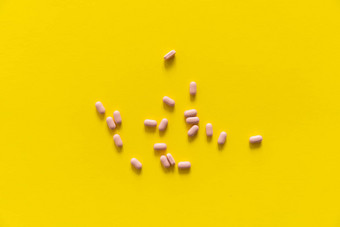 粉红色的药片黄色的背景医学药物治疗止痛药平板电脑医生药物抗生素维生素治疗药店主题前视图药片分散黄色的表面