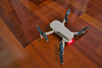 无人机坐着木地板上光指示死电池室内无人机飞行