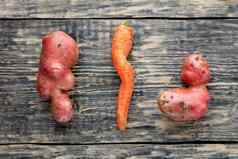 丑陋的土豆扭曲的胡萝卜饱经风霜的木背景蔬菜食物浪费概念前视图特写镜头