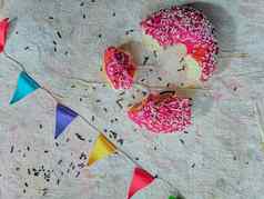 平躺片段粉红色的甜甜圈色彩斑斓的三角形光织物背景
