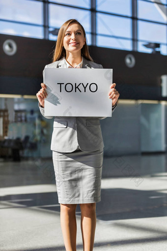 肖像女商人站持有白色董事会东京标志到来区域机场