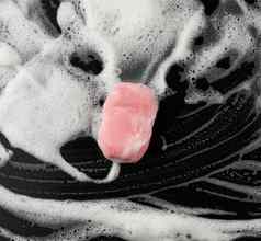 白色肥皂泡沫粉红色的肥皂黑色的背景前视图