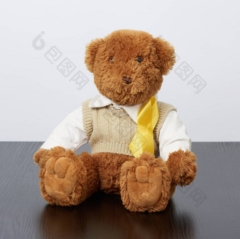 棕色（的）泰迪熊坐在黄色的<strong>丝绸</strong>丝带<strong>黑</strong>色的木