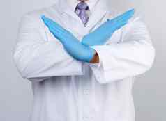 医生男人。白色外套蓝色的乳胶手套交叉手臂