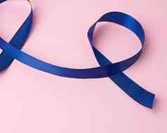 黑暗蓝色的丝绸丝带扭曲的循环粉红色的背景