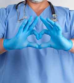 医生蓝色的统一的乳胶手套显示心手势