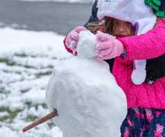 蹒跚学步的女孩玩雪前面花园