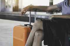 女人橙色手提箱行李袋坐着火车站
