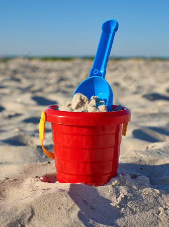 婴儿红色的塑料桶沙子铲海滨