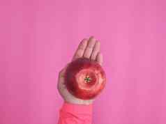 红色的成熟的苹果女手粉红色的背景