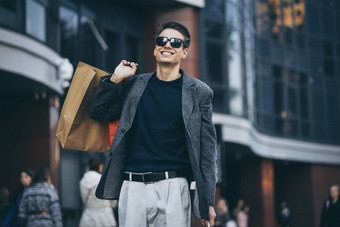 时尚的年轻的男人。太阳镜走城市街享受黑色的星期五购物时尚的商店城市