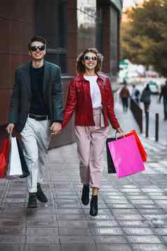 前面视图休闲夫妇购物者运行街相机持有色彩斑斓的购物袋