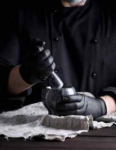 烹饪黑色的乳胶手套持有石头砂浆胡椒