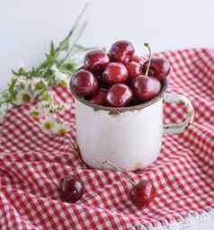 白色铁杯子成熟的浆果红色的樱桃
