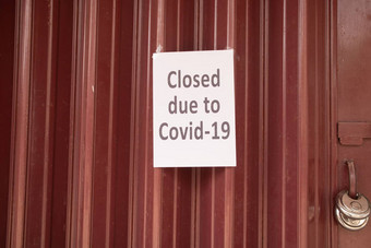 关闭由于冠状病毒科维德标志关闭快门通过前面商店商店由于冠状病毒爆发