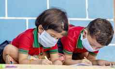 孩子们忙写作医疗脸面具穿由于科维德冠状病毒爆发流感大流行学校孩子们绘画首页封锁