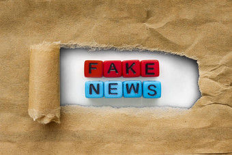 棕色（的）包卡夫纸撕裂揭示红色的蓝色的多维数据集单词假的新闻概念假的新闻
