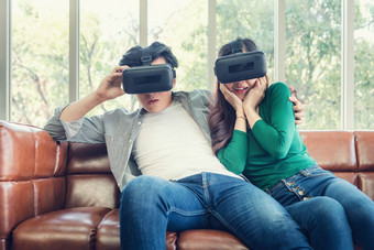 年轻的夫妇有趣的看视频虚拟现实夫妇爱享受电子护目镜游戏沙发上娱乐创新生活方式概念