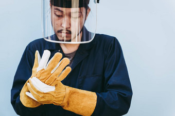 焊接工人穿个人安全设备保护概念肖像机械杂工站穿安全皮革手套脸盾金属焊接工作车间