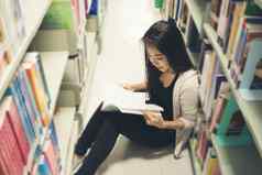 年轻的漂亮的亚洲学生阅读图书馆教育