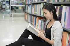 年轻的漂亮的亚洲学生阅读图书馆教育