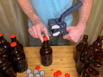 工艺啤酒酝酿首页男人。关闭棕色（的）玻璃啤酒瓶塑料封口机木表格红色的皇冠帽水平图像