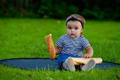 漂亮的婴儿女孩坐在草坪上花园持有新鲜的魔杖