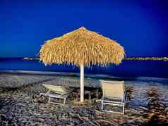 稻草伞甲板椅子美丽的海滩晚上