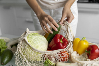 女人手持有可重用的生态纺织杂货店袋蔬菜需要红色的黄色的胡椒浪费塑料免费的概念女孩持有网棉花购物者蔬菜