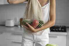 女人手持有可重用的杂货店袋蔬菜水果浪费塑料免费的概念女孩持有网棉花购物者蔬菜生态