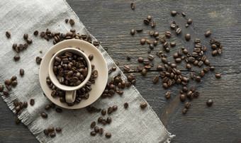 咖啡杯填满新鲜的Arabica罗布斯塔咖啡豆子分散咖啡豆子亚麻纺织木表格