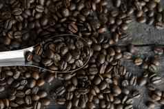 新鲜的烤Arabica咖啡豆子金属勺子分散咖啡豆子木表格