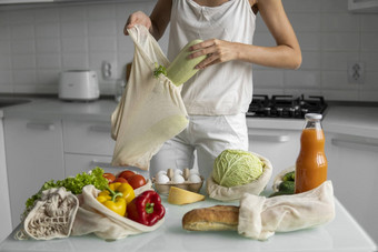 女人的手持有可重用的杂货店袋蔬菜厨房首页需要西葫芦浪费塑料免费的概念网棉花购物者蔬菜生态