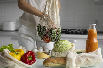 女人手持有可重用的生态纺织杂货店袋蔬菜水果浪费塑料免费的概念女孩持有网棉花购物者蔬菜