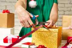 女人手包装圣诞节礼物黄金盒子红色的丝带Diy礼物包装