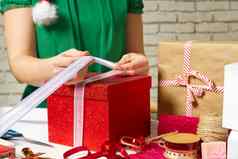 女人手包装圣诞节礼物红色的盒子白色丝带Diy礼物包装
