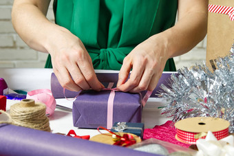 女人包装圣诞节礼物紫罗兰色的包装纸女人手包装圣诞节礼物Diy礼物包装概念